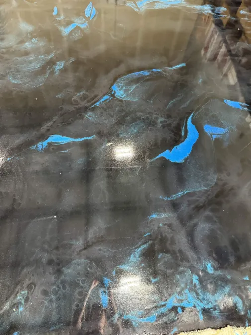 Black metallic epoxy floor with electric blue swirls and mirror-gloss finish installed by IronCoat Epoxy Co. in DFW