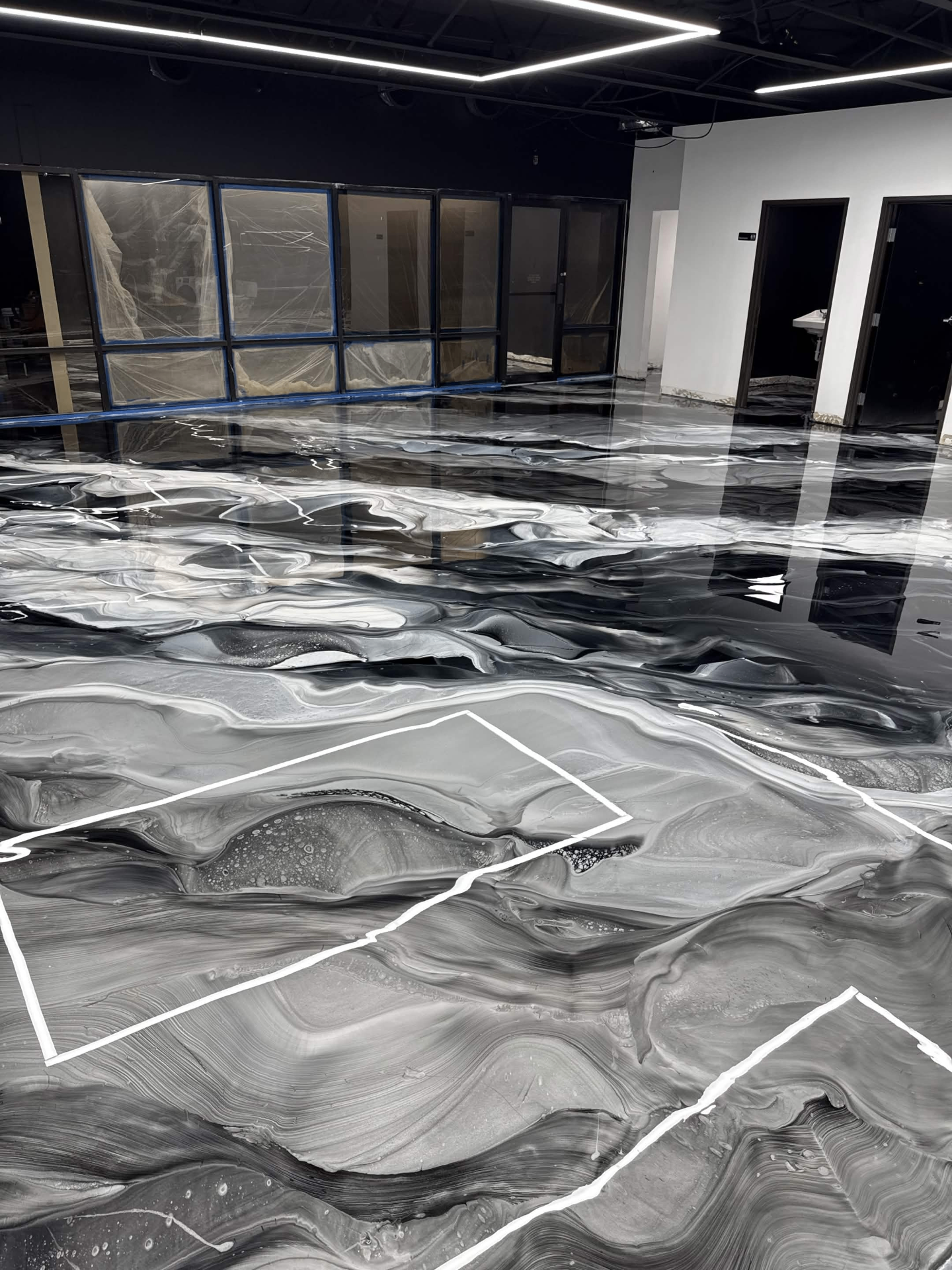 Black, white and silver metallic epoxy floor with marble-style swirls and mirror-gloss finish installed by IronCoat Epoxy Co. in a DFW commercial space
